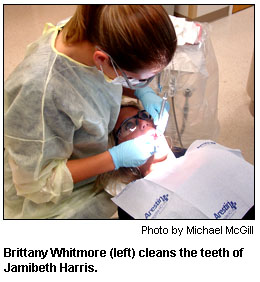 Brittany Whitmore (left) cleans the teeth of Jamibeth Harris.