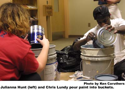 Julianna Hunt (left) and Chris Lundy pour paint into buckets