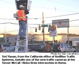Ted Ylauan, from the California office of Redlflex Traffic Systems, installs one of the new traffic cameras at the Turner McCall / Hicks Drive intersection in Rome.