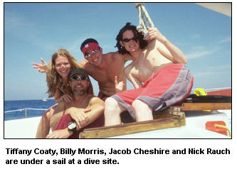 Tiffany Coaty, Billy Morris, Jacob Cheshire and Nick Rauch are under a sail at a dive site.