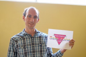 Chris Hart, instructor of mathematics and coordinator of Safe Zone, holds up the program’s logo which will be posted on certified members’ office doors. Photo by Brooke Allen.