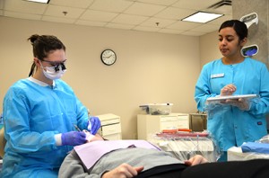 Dental hygiene students Emilee Brussee (left) and Clara Reyes focus on cleaning their patient's teeth in the lab at Heritage Hall. 