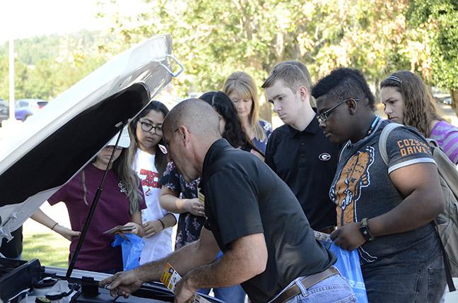 Bryce Wood of Jim’s Tires demonstrates to GHC students how to locate the car battery and attach jumper cables. Photo by Xavier Freeman
