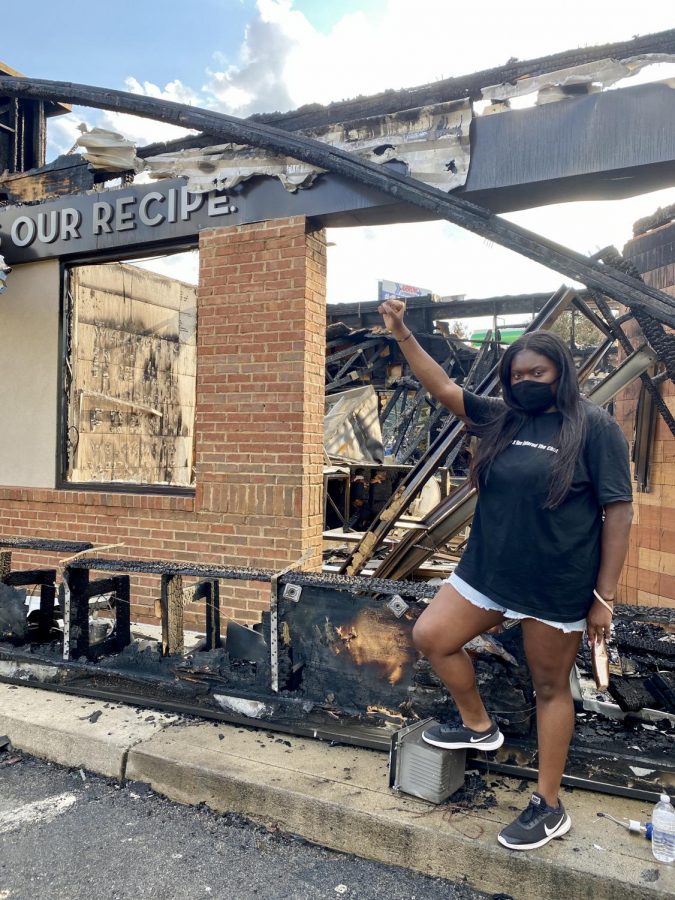 GHC student Alexis Johnson holding up her fist standing in solidarity with victims of police brutality. Standing in front of the burned down Wendys.