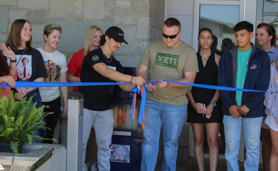 Students Jagger Leavens (left) and Mason Woodward (right) cut the ribbon to the Little Free Library marking the official opening of the GHC site. 